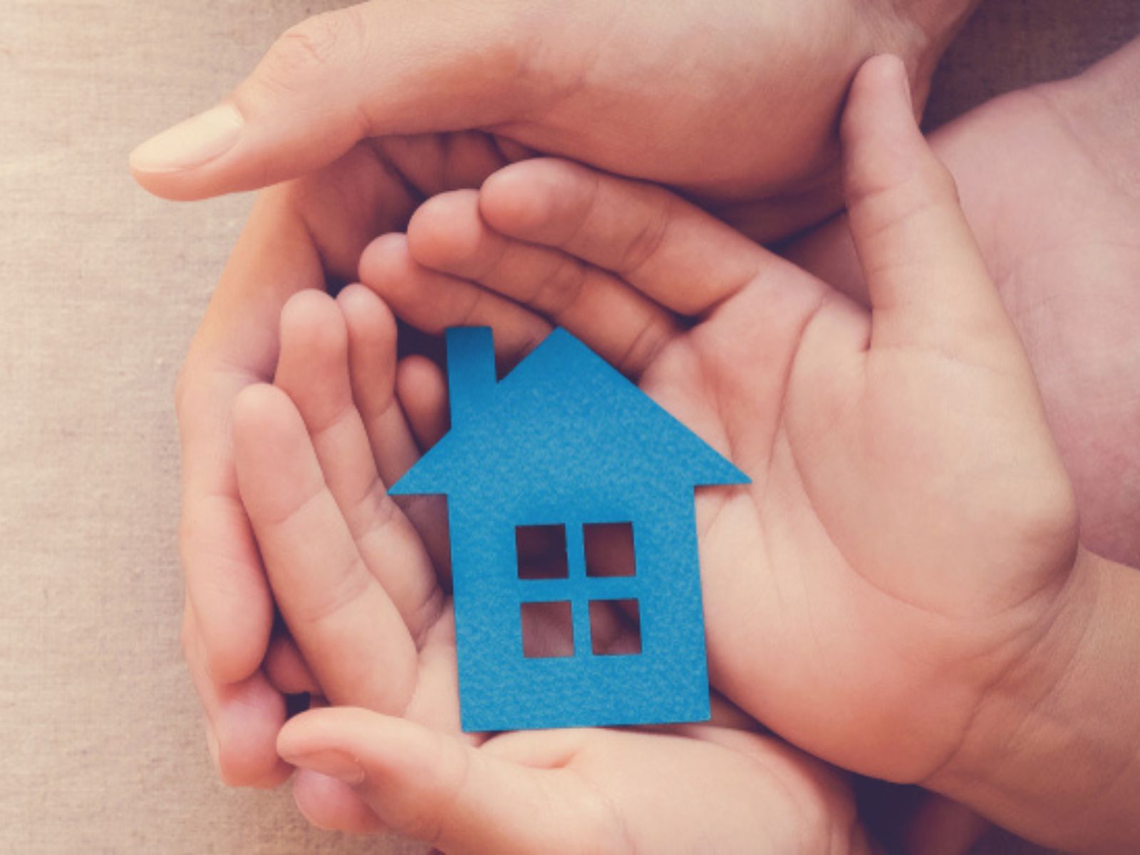 hands holding a cut out of a blue house